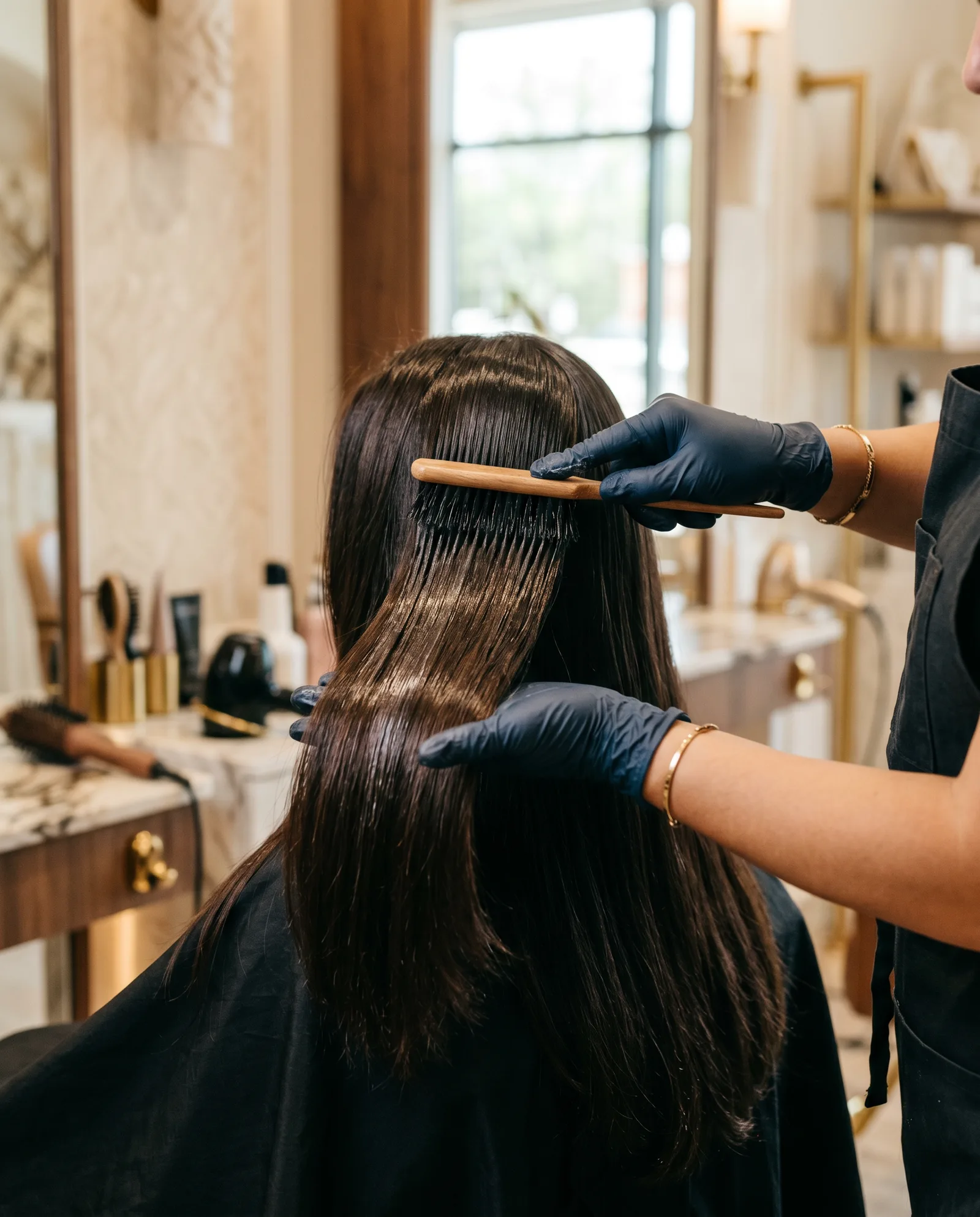 Stylist smoothing a keratin treatment through long glossy dark hair in a Palo Alto salon